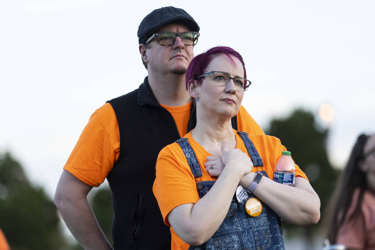 Michael Close, left, and his wife Kati, listen to a speaks during the "Wear Orange" e ...