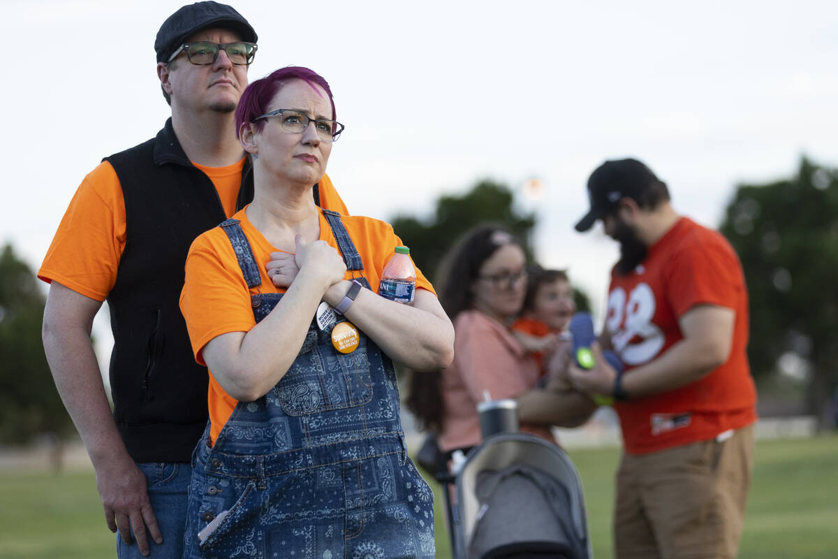 Michael Close, left, and his wife Kati, listen to a speaks during the "Wear Orange" e ...