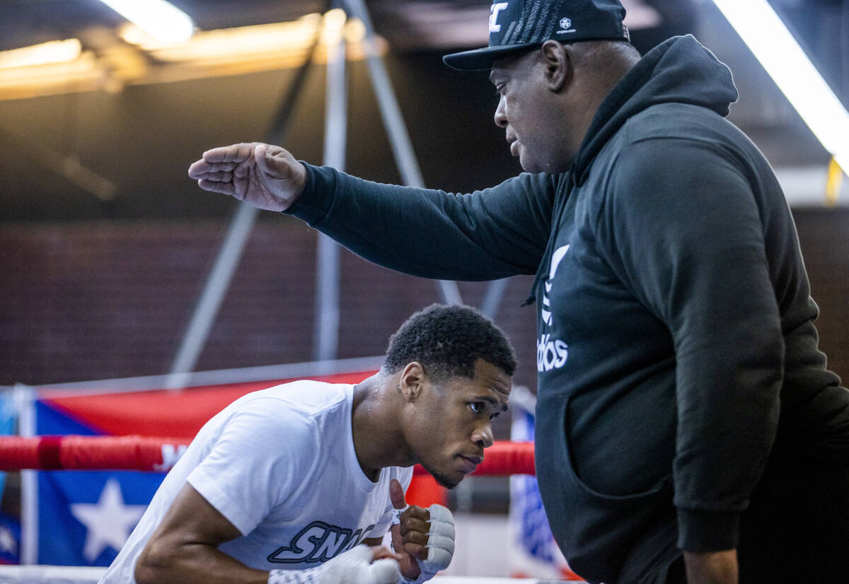 WBC lightweight boxer Devin Haney ducks under an arm by trainer Rodney Crisler in the ring duri ...