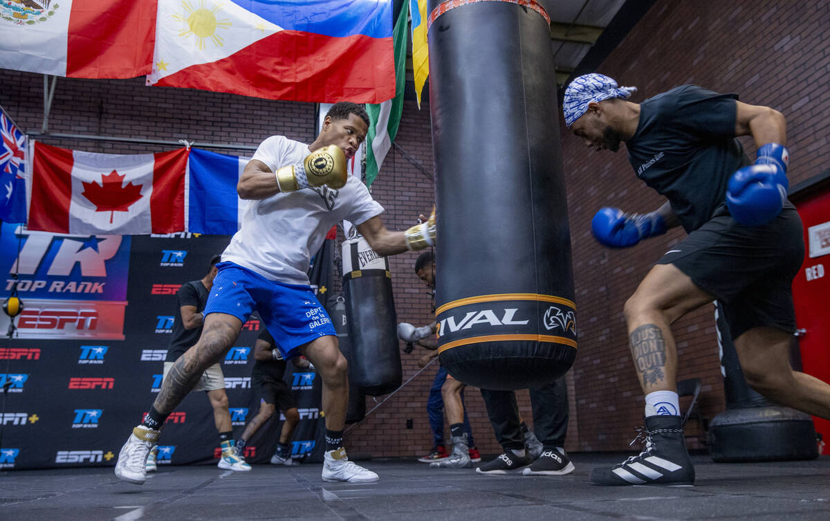 WBC lightweight boxer Devin Haney, left, throws a punch on a heavy bag as boxer Amari Jones hit ...