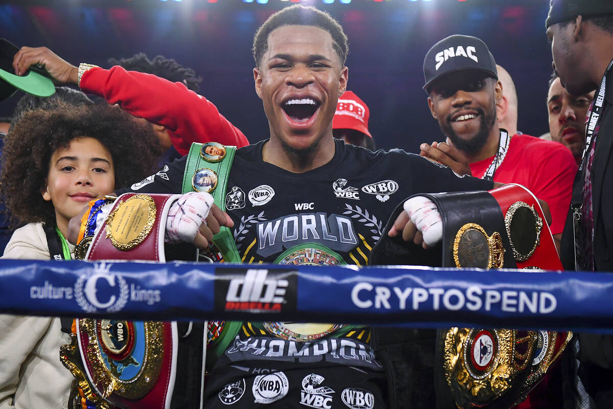 Devin Haney, center, of the United States, poses with his belts after defeating Australia's Geo ...