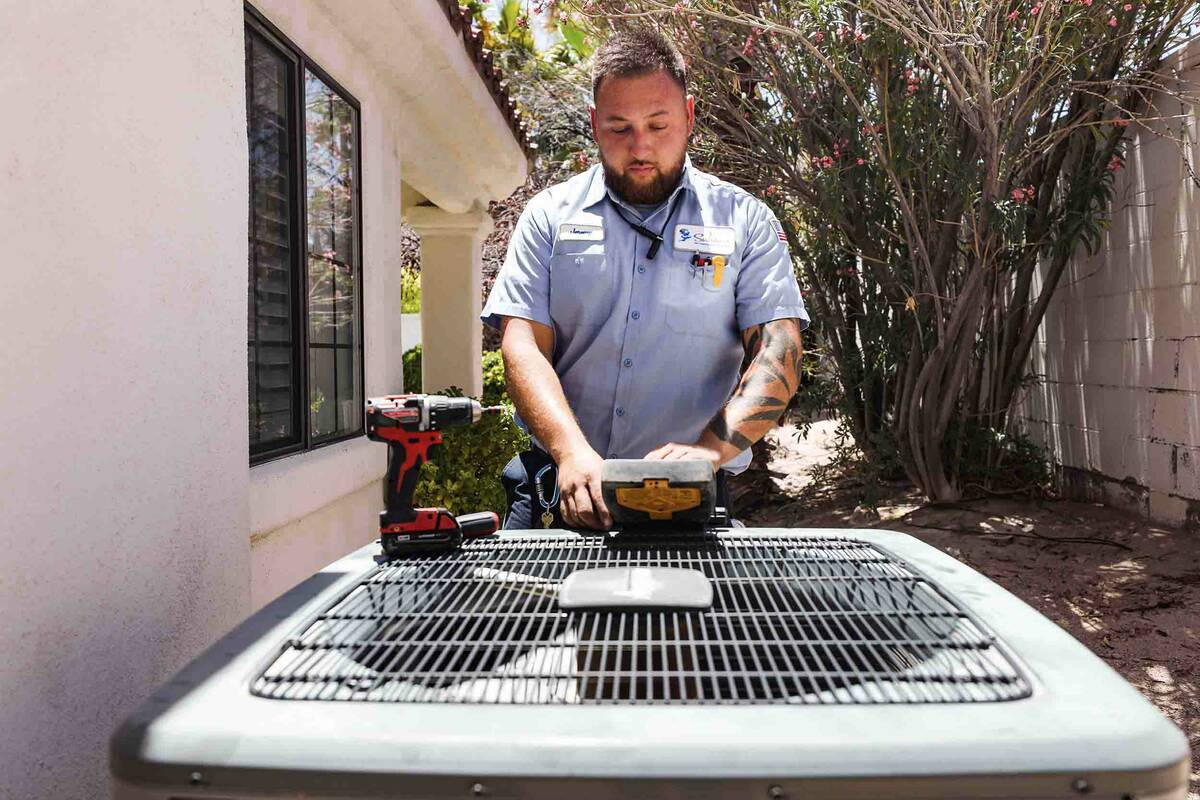 Service technician with Sahara Air Conditioning & Heating Jeremy Rojas repairs an air condi ...