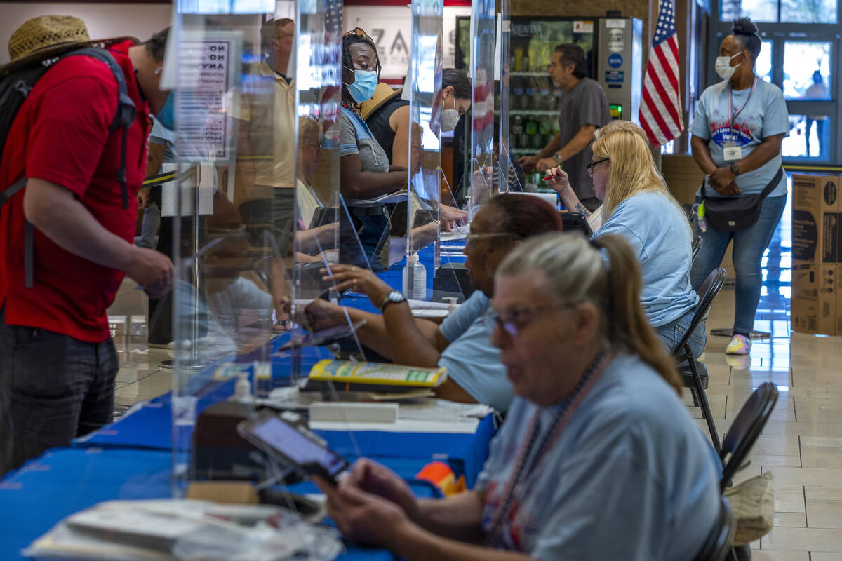 Area residents, left, are assisted by the Clark County Election Department personnel on the las ...
