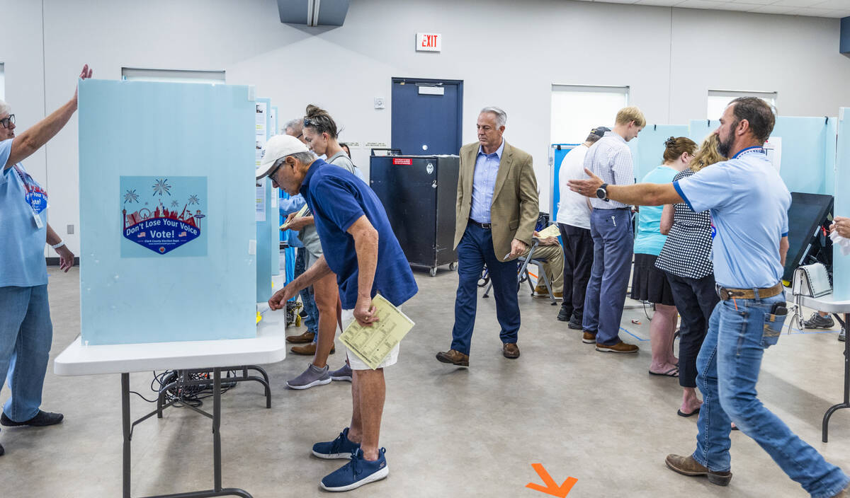 Sheriff Joe Lombardo, center, is directed to his booth to cast his vote during the Nevada prima ...