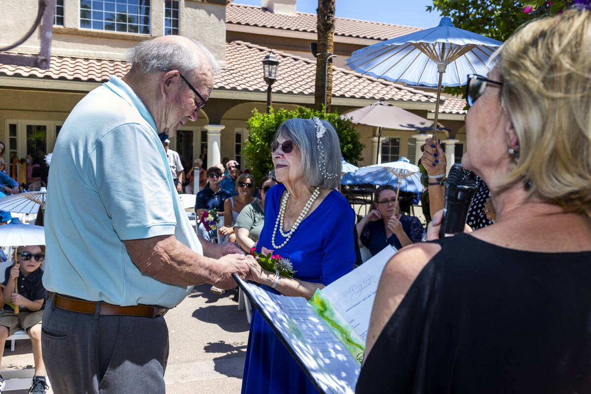 Groom John Hansell, left, and bride Carolyn Brylinski, center, hold hands as they listen to wor ...