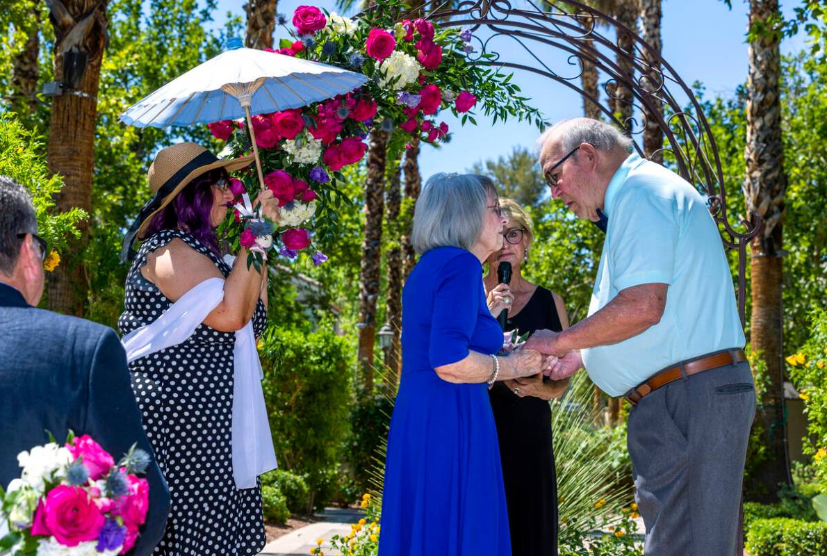 Bride Carolyn Brylinski, center, holds hands with groom John Hansell, right, as they listen to ...
