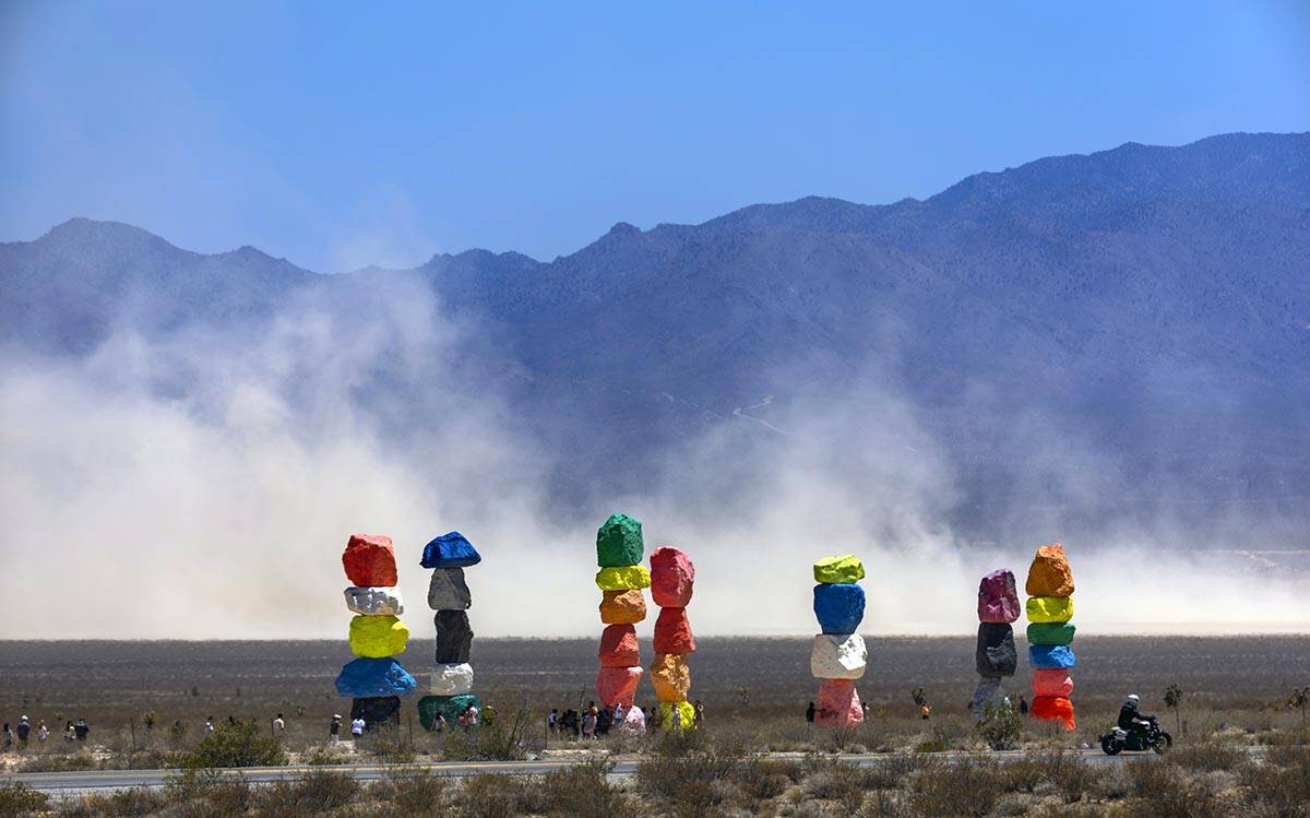 Seven Magic Mountains with giant dust clouds coming off of the dry lake bed as a backdrop while ...