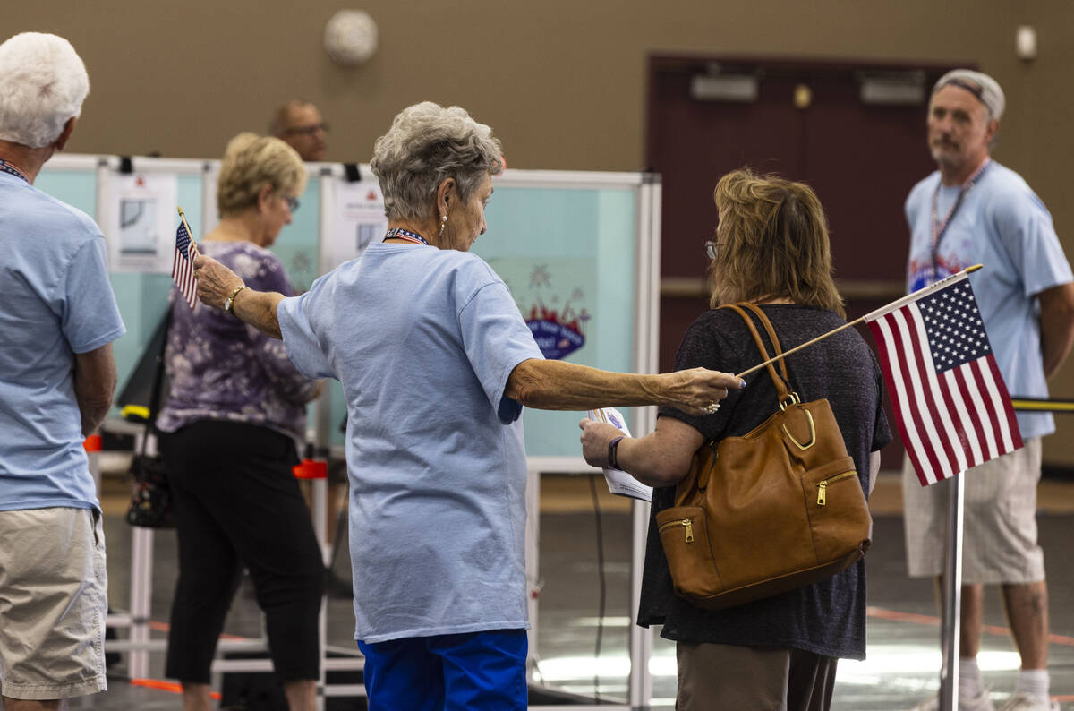 Election volunteer Penny Busse greets a voters as they arrive at a polling station at Desert Br ...