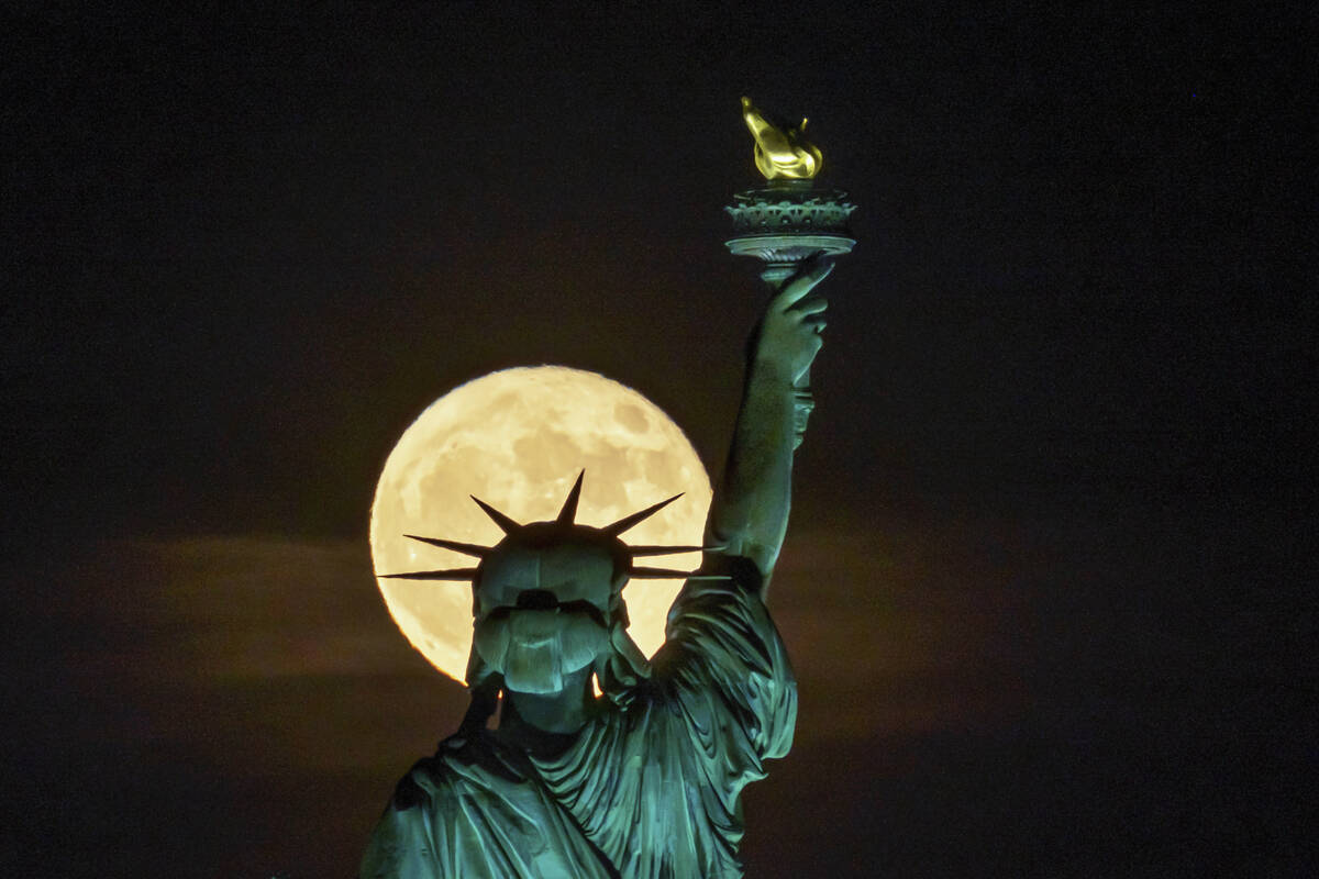 The Strawberry Supermoon rises in front of the Statue of Liberty in New York, late Tuesday, Jun ...