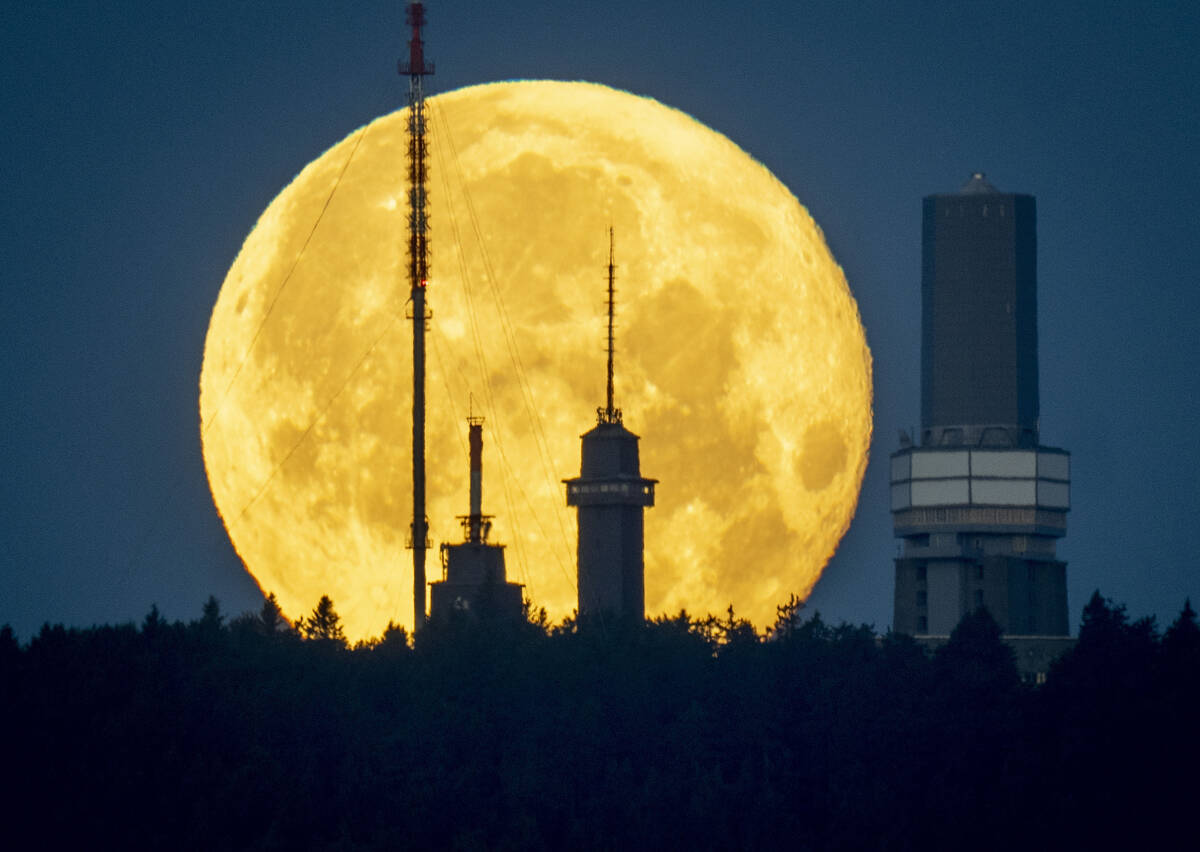 The full moon sets behind the telecommunication devices on top of the Feldberg mountain near Fr ...