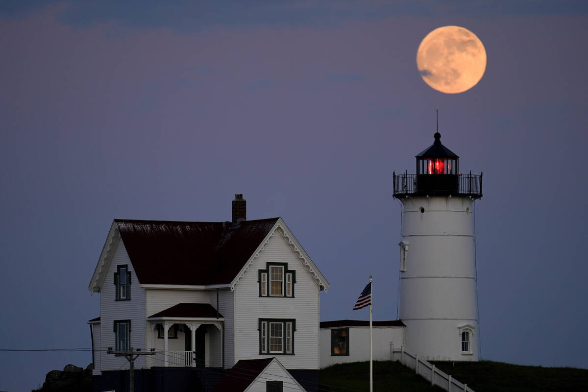 A waxing gibbous moon is seen at 98% percent full as it rises near the Nubble Light, Monday, Ju ...