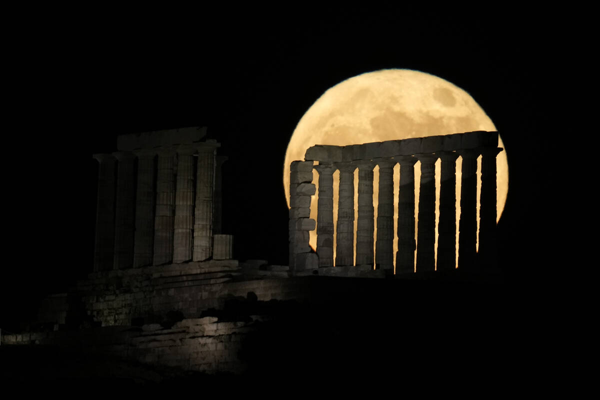 The strawberry full moon rises behind the ancient temple of Poseidon at Cape Sounion, about 70 ...