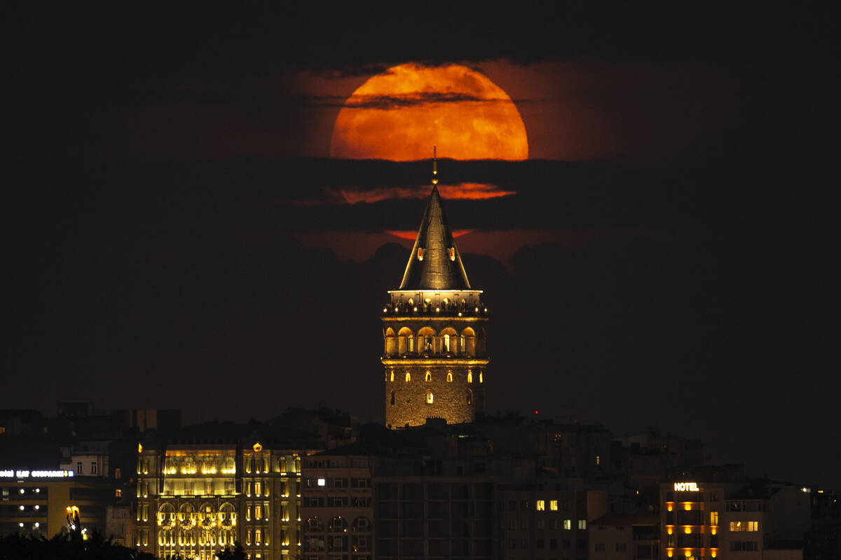A supermoon rises behind the Galata Tower in Istanbul, Turkey, Tuesday, June 14, 2022. The moon ...