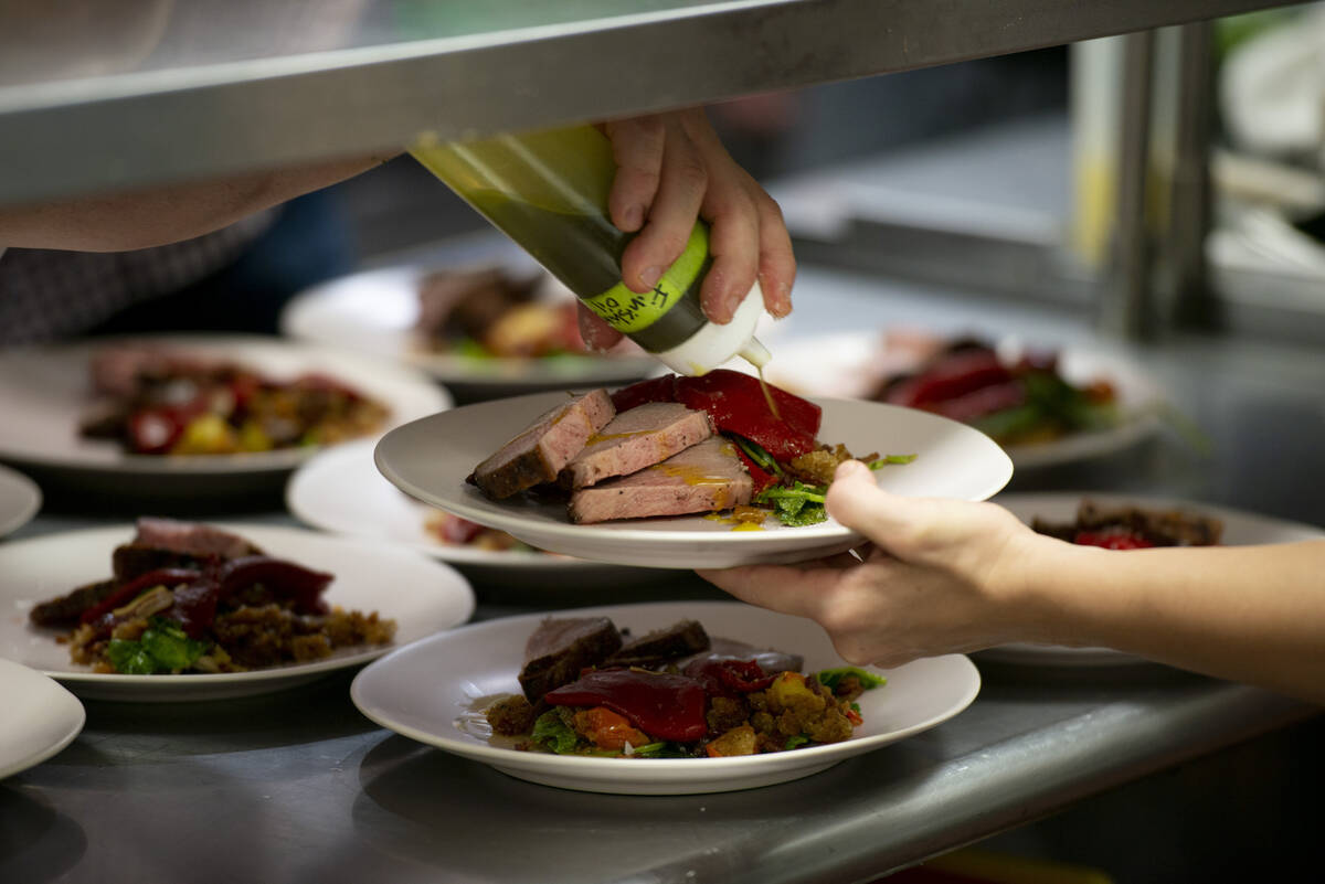 Chef Jeffrey Weiss finishes the fourth dish, roast pork presa with Benton’s bacon migas and p ...