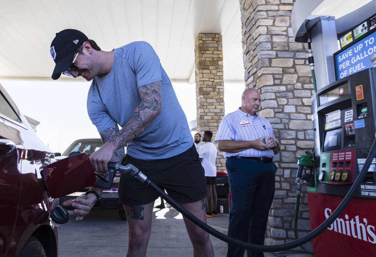 Golden Knights goaltender Logan Thompson pumps gas to a customer as Bob Kelly, right, general m ...