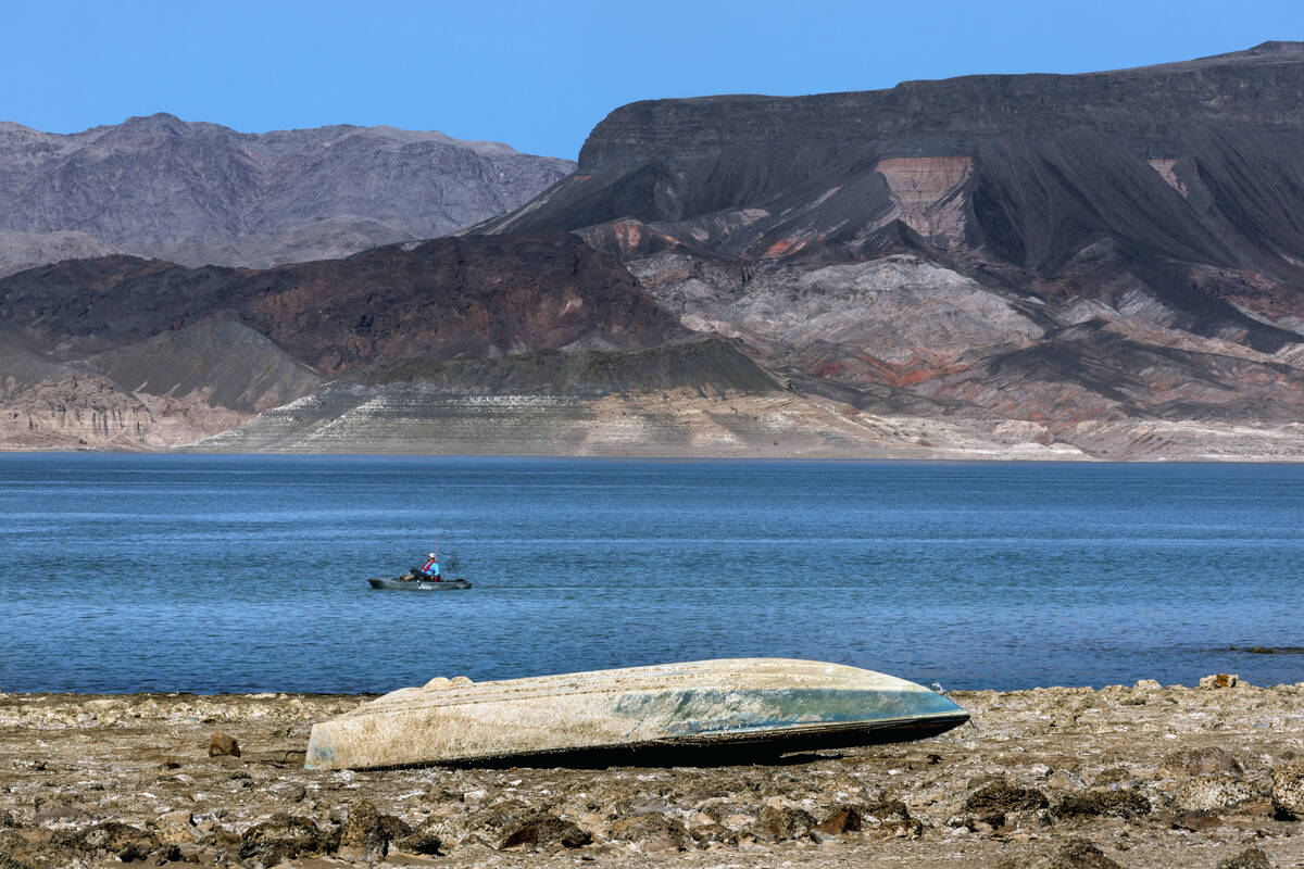 A boater looks to another sunken boat revealed on shore as the water level continues to decline ...