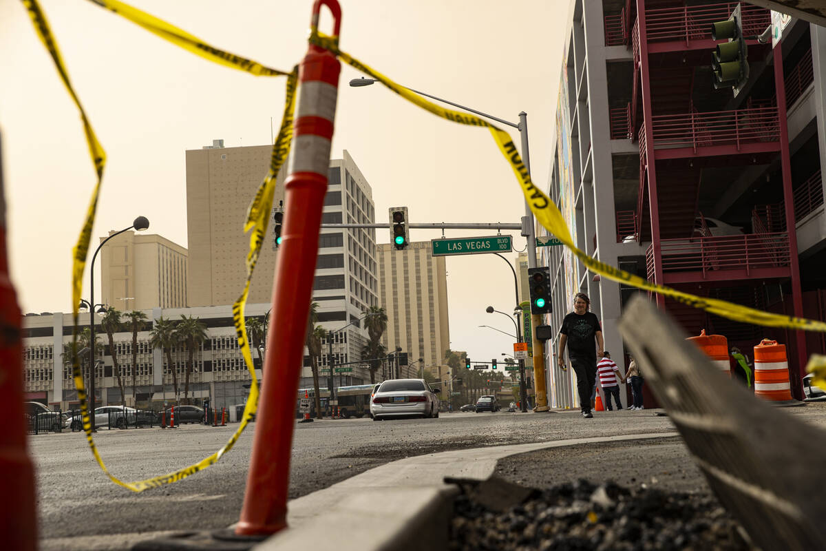 Pedestrians cross Las Vegas Boulevard in downtown as winds bring in a dust storm on Monday, Apr ...