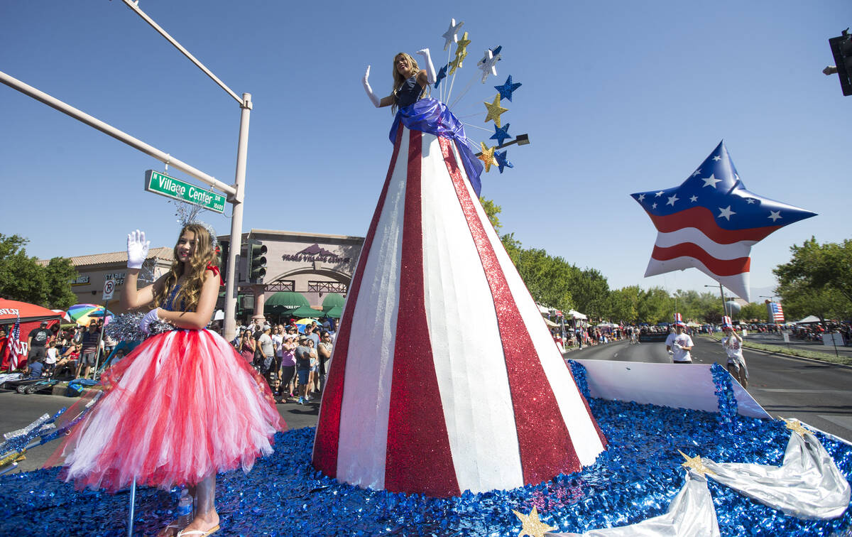 Participants riding the Pardee Homes "America Standing Tall" float wave to people in the crowd ...