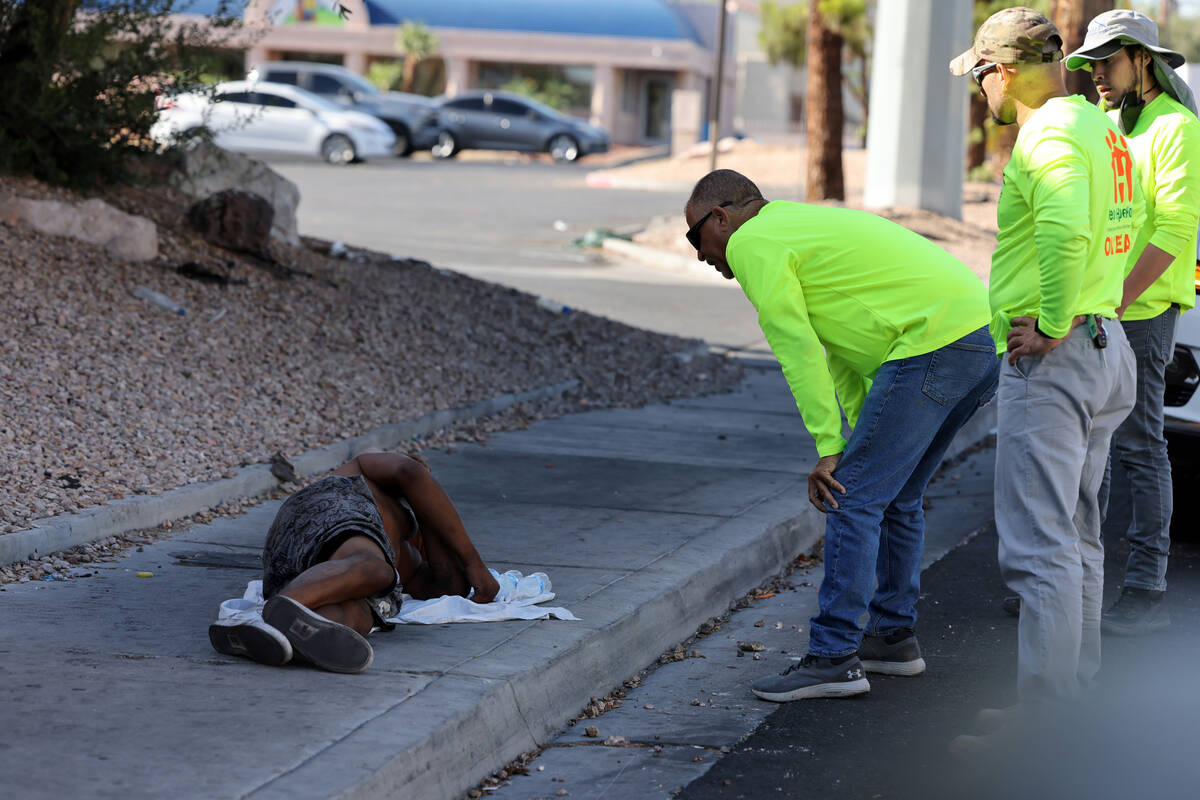 HELP of Southern Nevada homeless response director Louis Lacey, left, offers water to a man dur ...