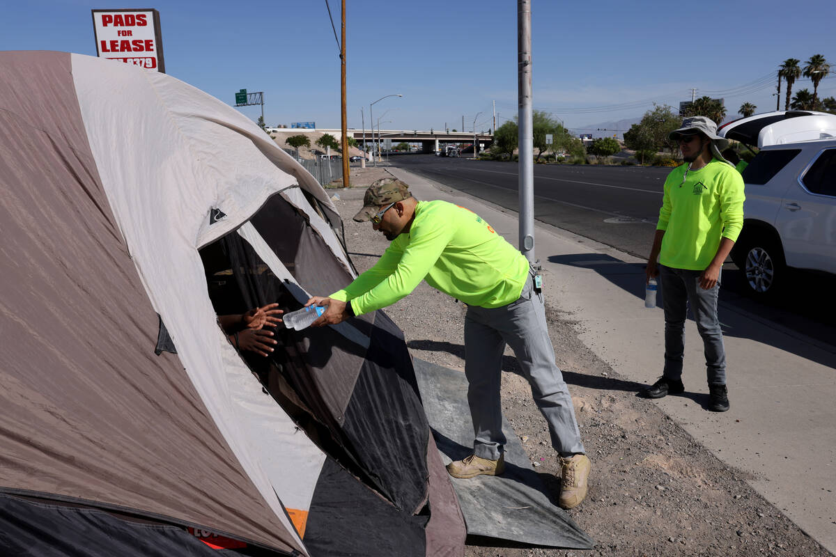 HELP of Southern Nevada's Abdul Hamdard offers water to a person sheltering in a tent on Boulde ...