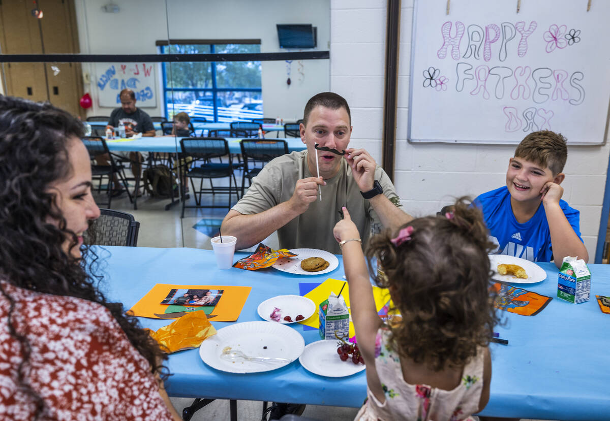 Jason Grace, center, entertains his daughter Erica, 2, with a paper mustache as his wife Leslie ...