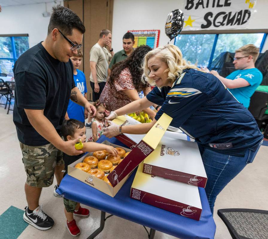 (From left) Peter Hyun looks down to see his son Leo, 2, make his own donut selection as Daniel ...
