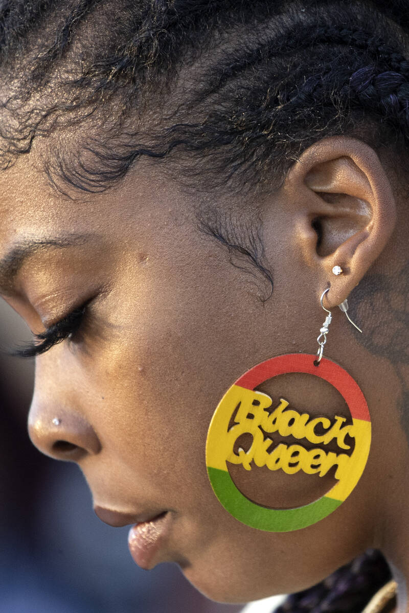 An attendee of a Juneteenth expo wears earrings that read “Black Queen” at World ...