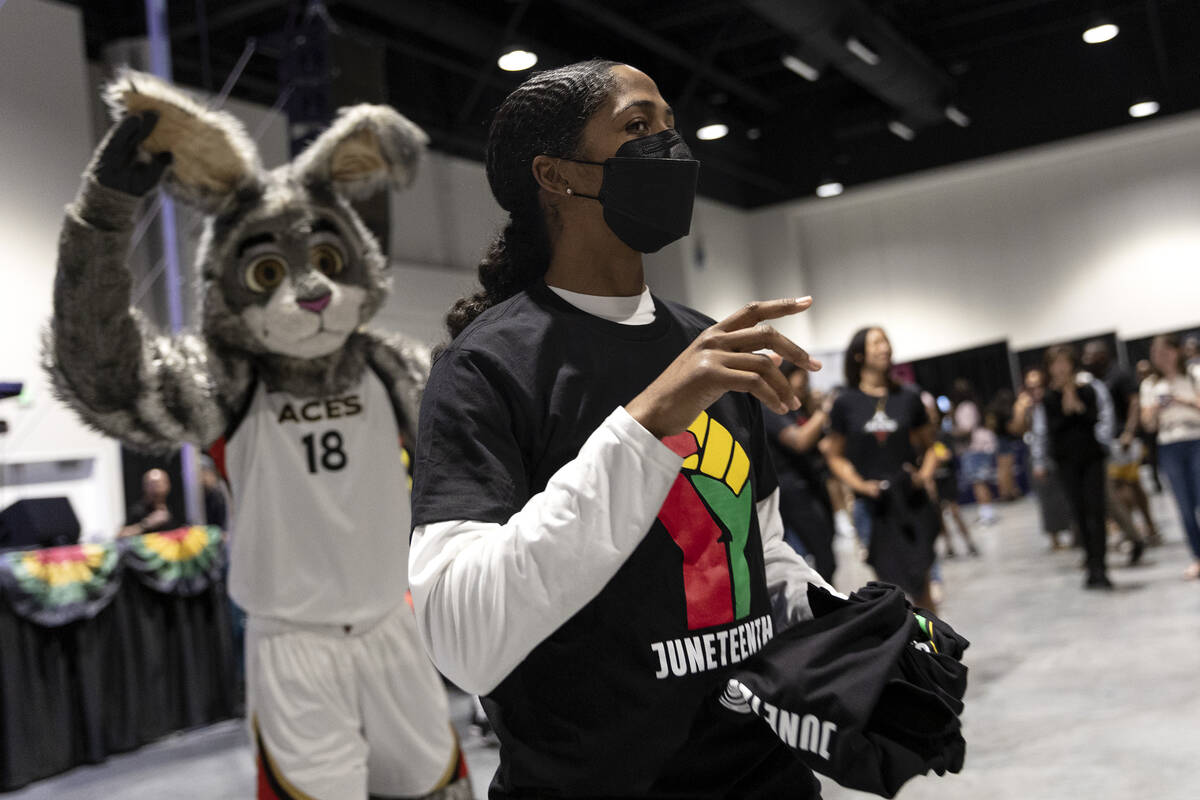 Las Vegas Aces guard Sydney Colson looks to throw a t-shirt to the crowd during a Juneteenth ex ...