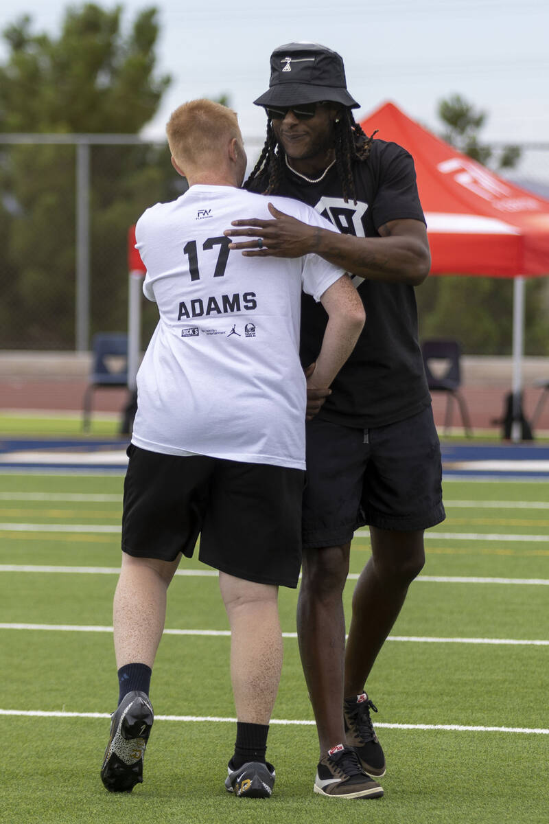 Raiders wide receiver Davante Adams hugs a young athlete participating in his youth football ca ...
