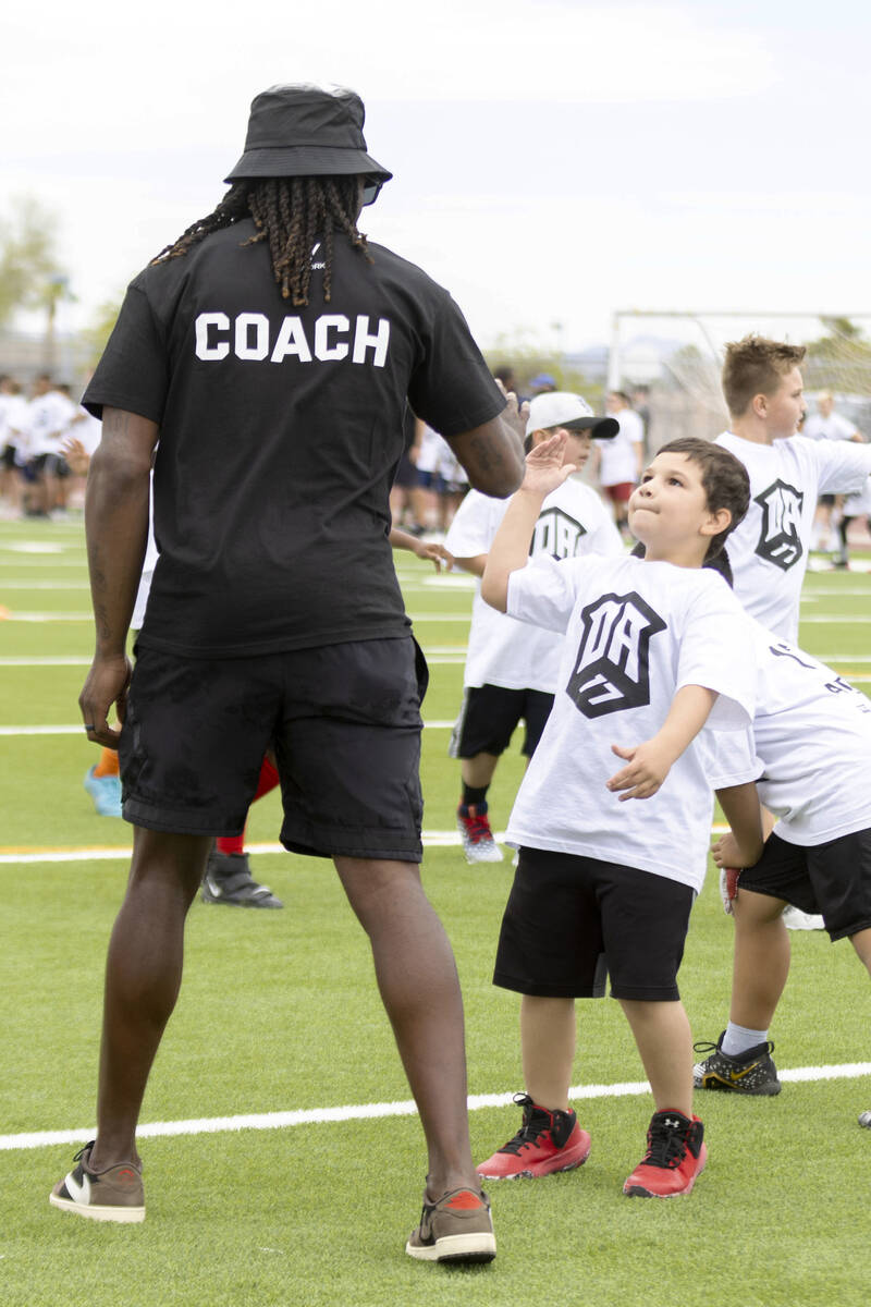 Raiders wide receiver Davante Adams gives a high five to a young athlete participating in his y ...
