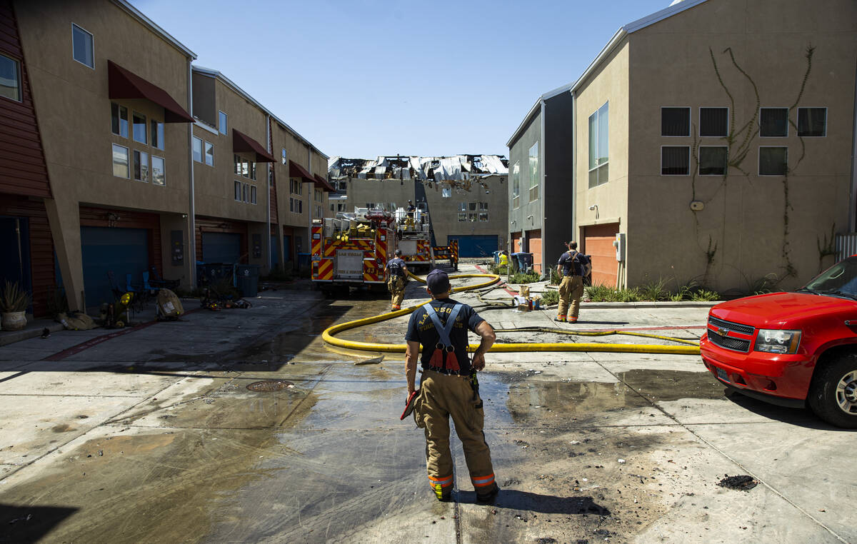 A firefighter surveys the scene where a fire damaged or destroyed at least 10 buildings at a co ...