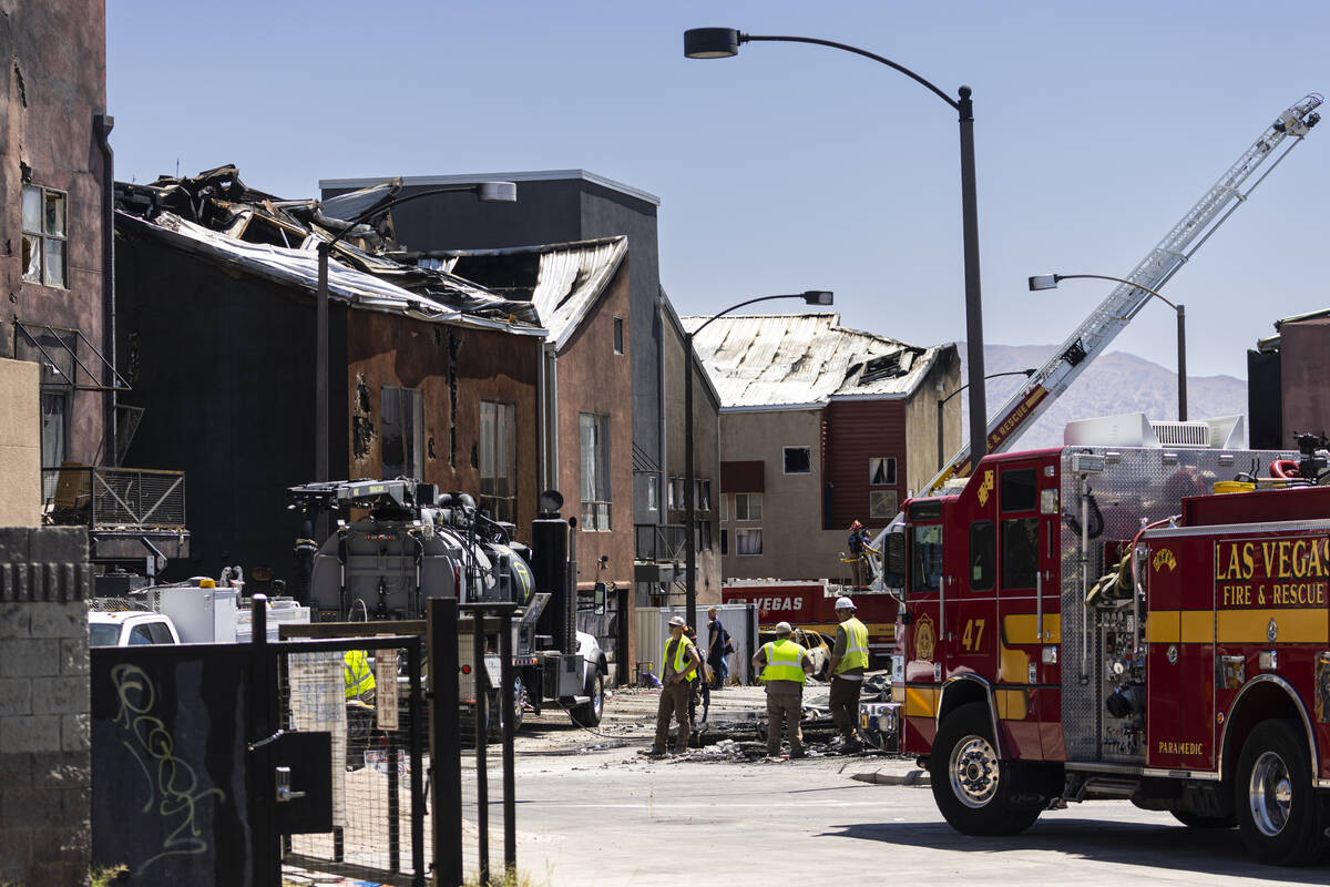 Firefighters and officials work at the scene where a fire damaged or destroyed at least 10 buil ...