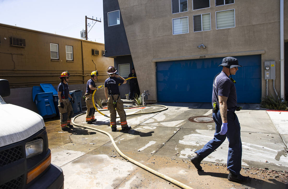 Firefighters work to put out a hotspot at the scene where a fire damaged or destroyed at least ...