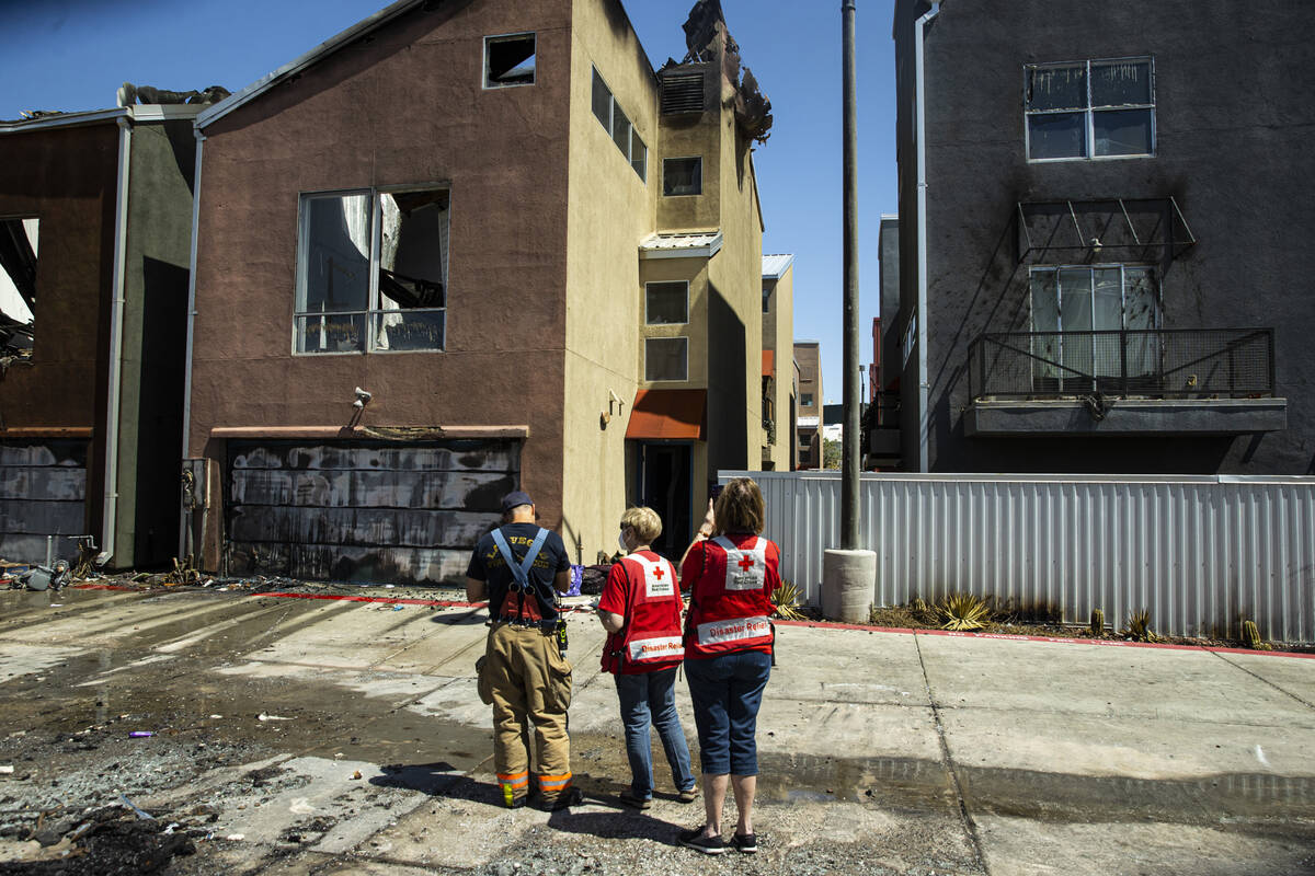 American Red Cross representatives survey the scene where a fire damaged or destroyed at least ...