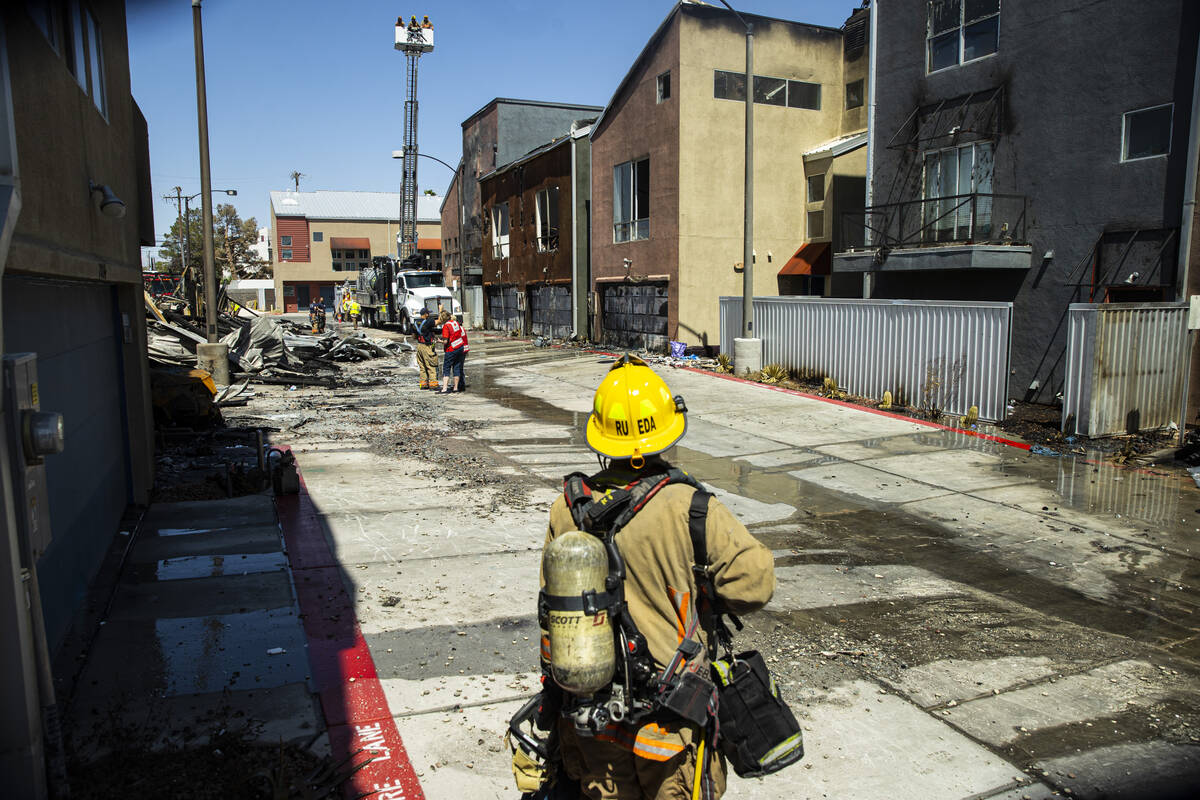 A firefighter surveys the scene where a fire damaged or destroyed at least 10 buildings at a co ...