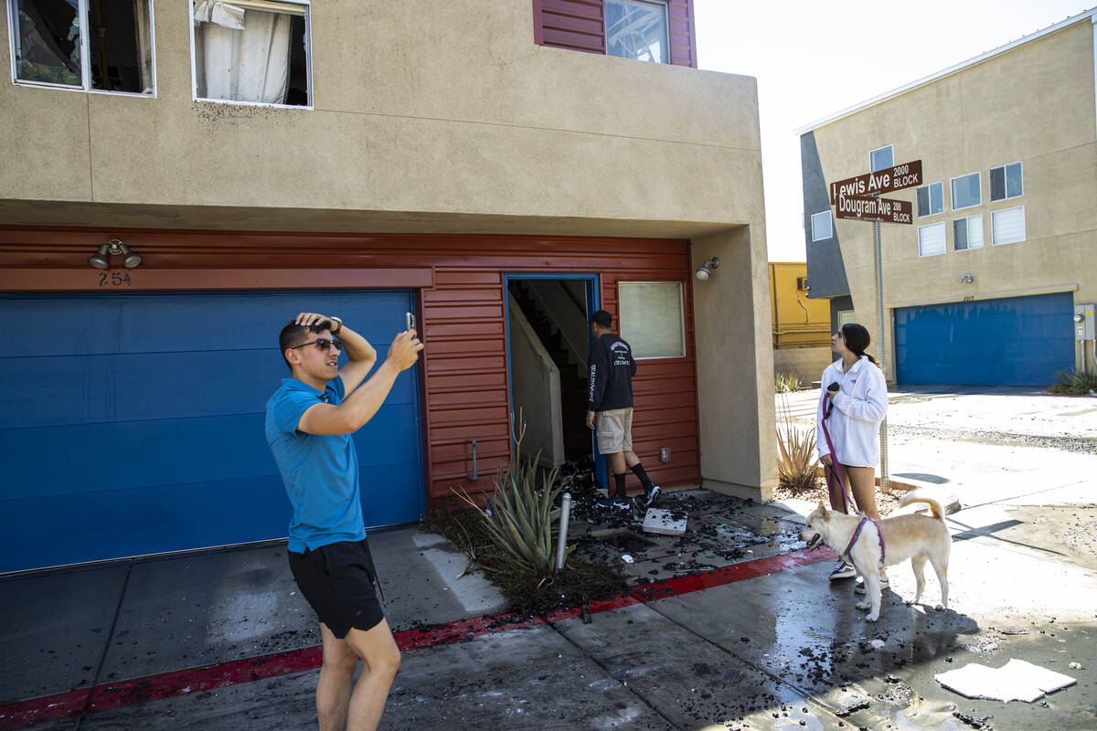Mason Mena, 21, left, documents the damage as his father, Junior Mena, peers into their home al ...