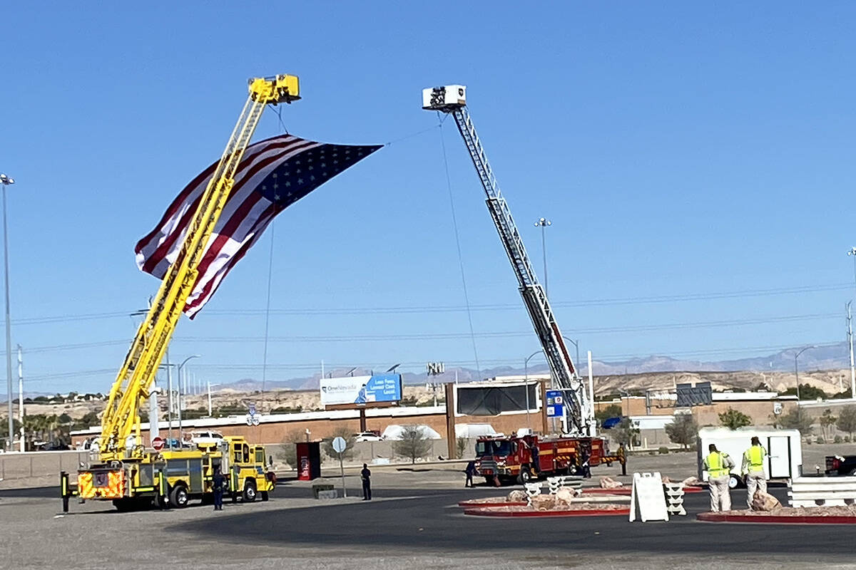 Members of the Las Vegas and Clark County fire departments stretch a flag across the church ent ...