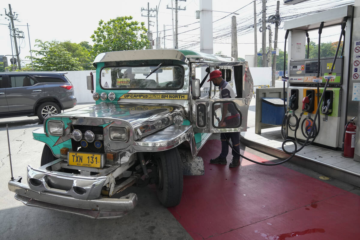 A passenger jeepney driver refuels his vehicle at a gasoline station in Quezon City, Philippine ...