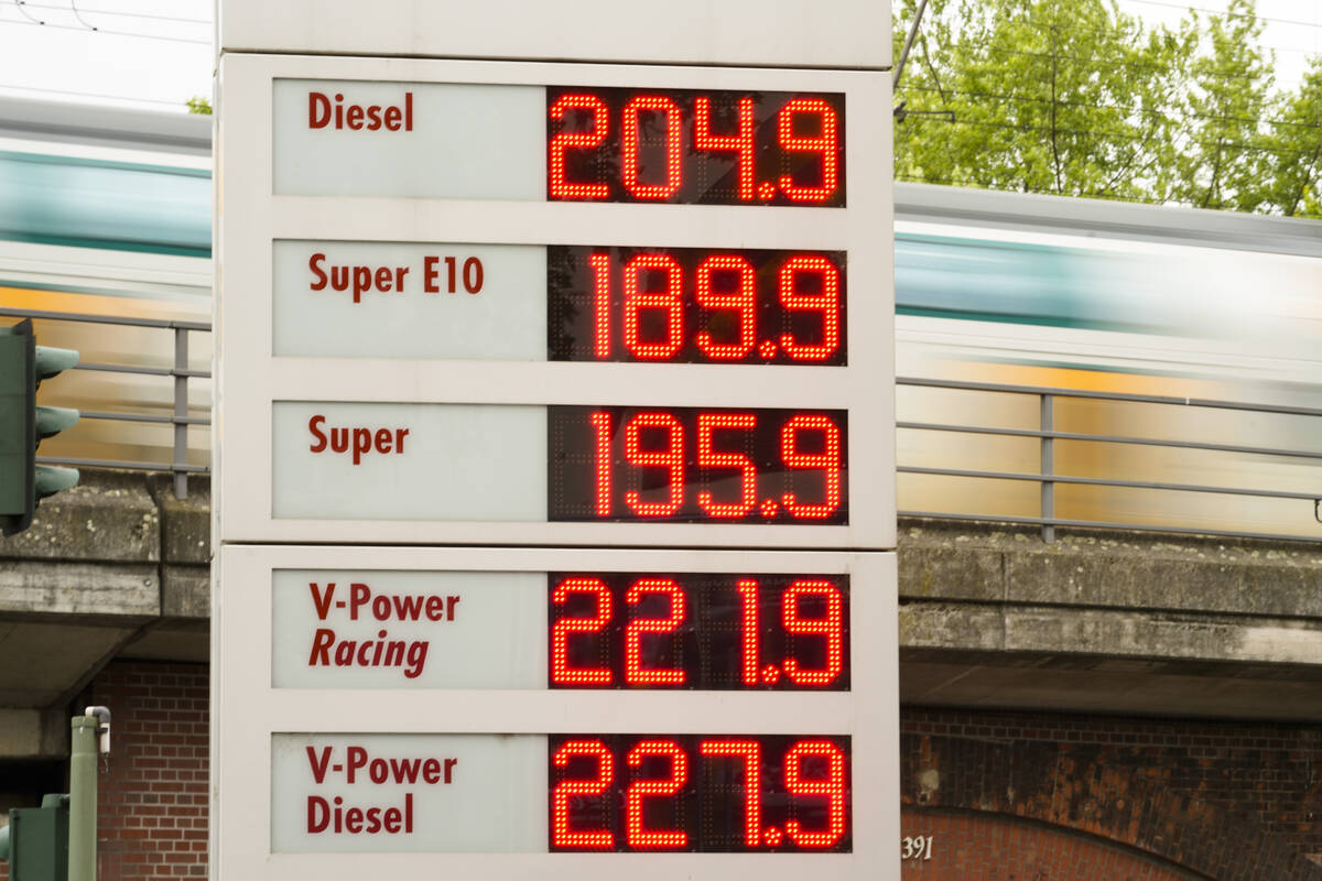 A public transport train drive behind a display with fuel prices at a gas station et in Berlin, ...
