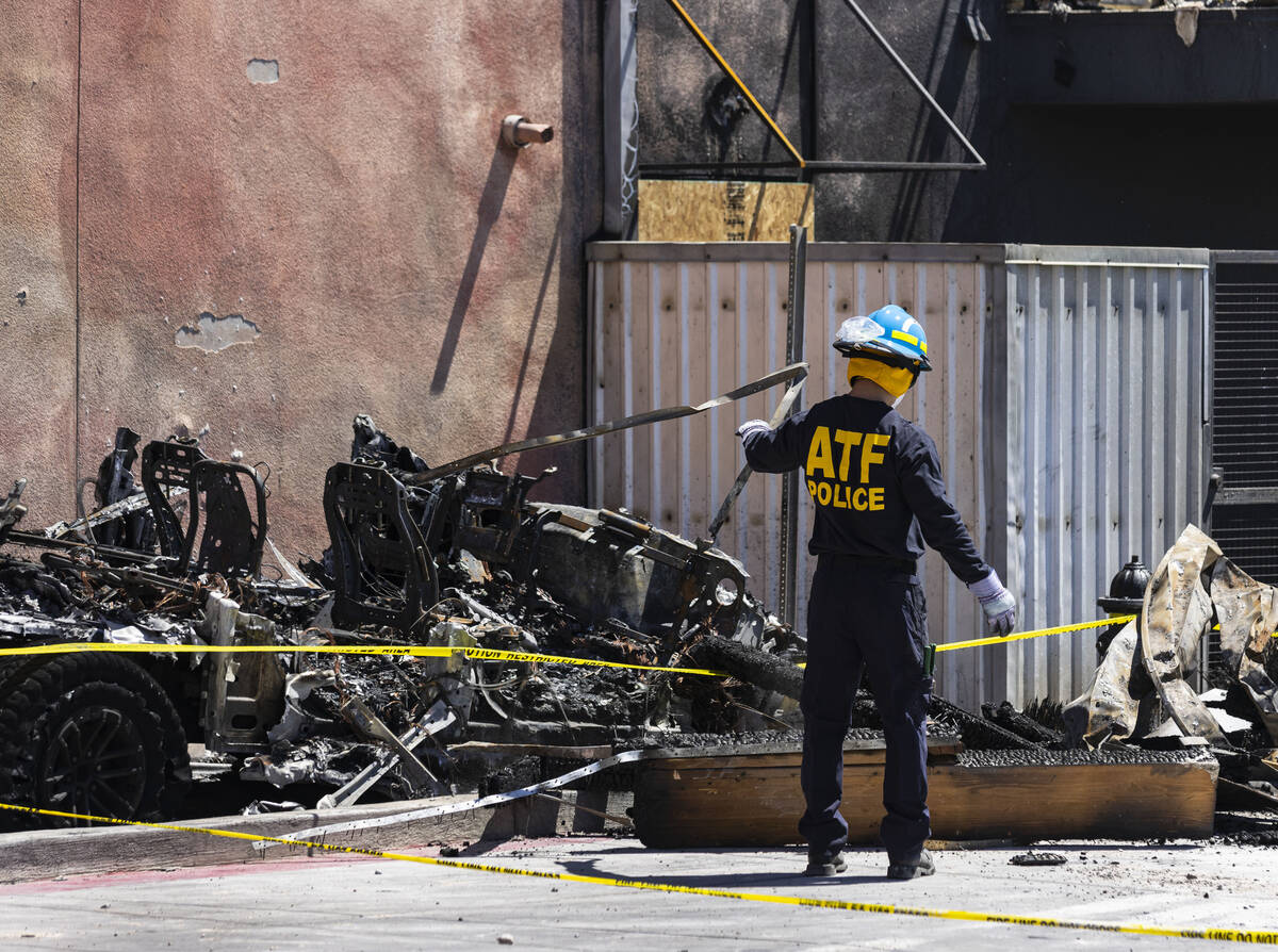 A member of the Bureau of Alcohol, Tobacco, Firearms and Explosives (ATF) looks through debris ...