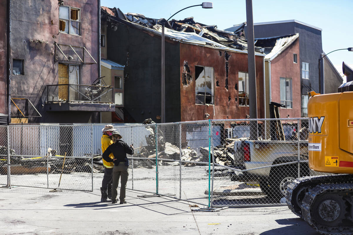 Investigators work the scene of the massive fire that torched 10 buildings and dozens of cars o ...