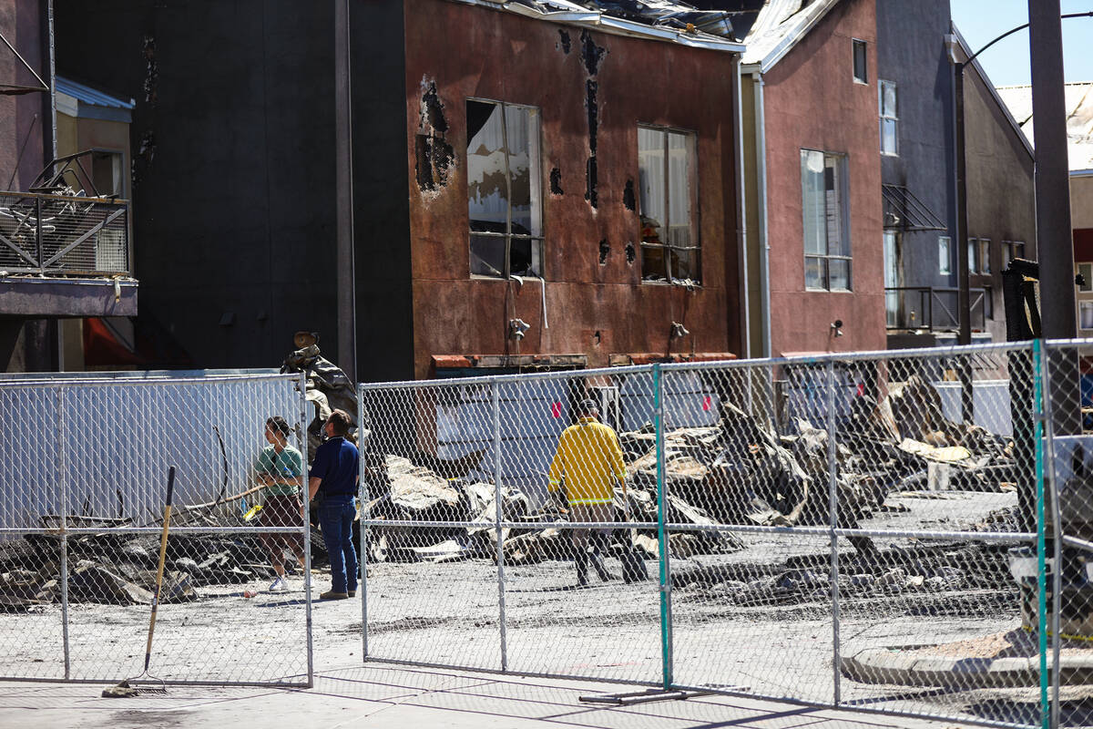 Investigators work the scene of the massive fire that torched 10 buildings and dozens of cars o ...