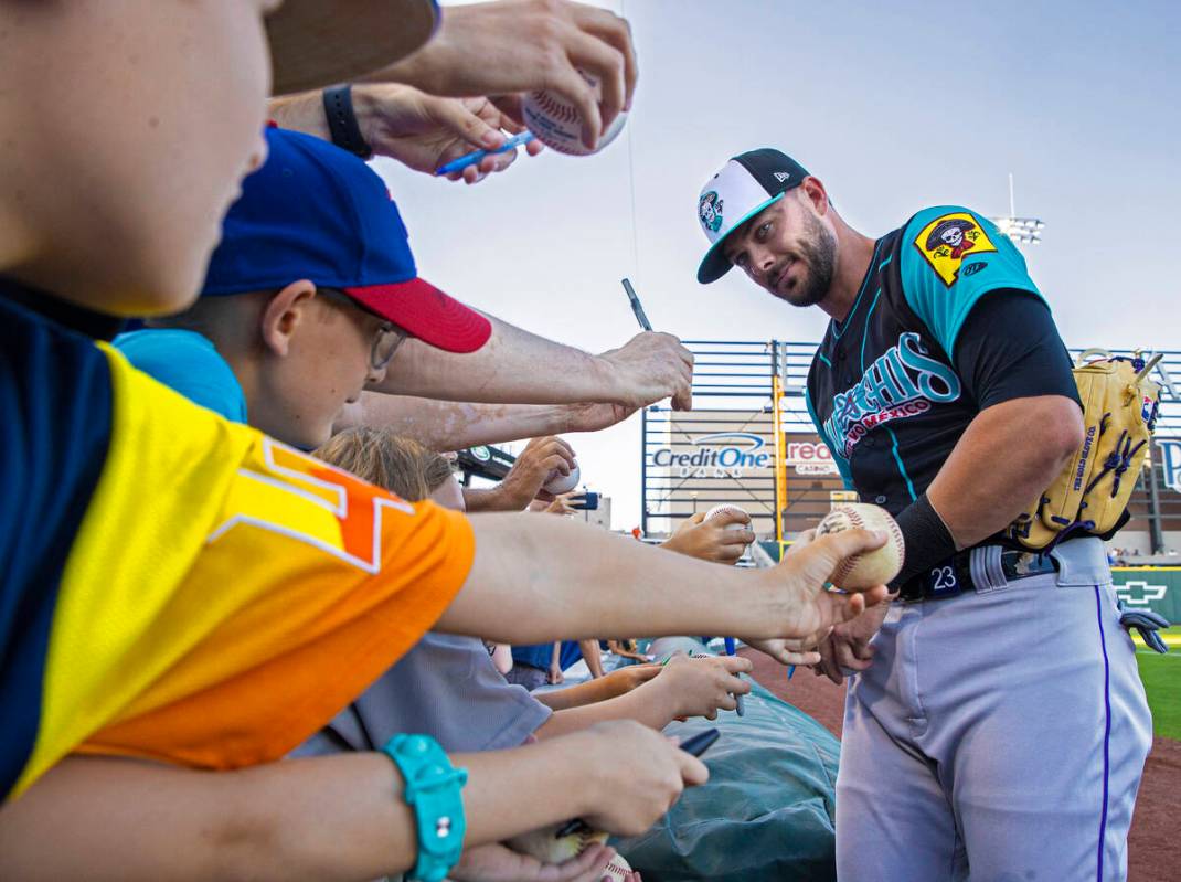 Colorado Rockies third baseman Kris Bryant, right, signs autographs during a rehab assignment w ...