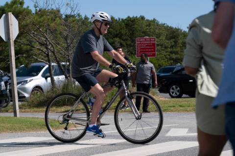 President Joe Biden pedals his bike towards a crowd at Gordons Pond in Rehoboth Beach, Del., Sa ...