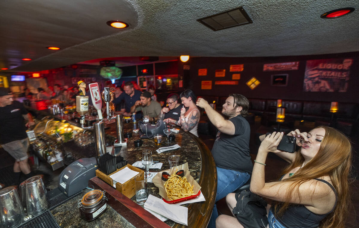 Patrons drink Jameson shots to toast the official start of the Atomic Liquors 70th anniversary ...