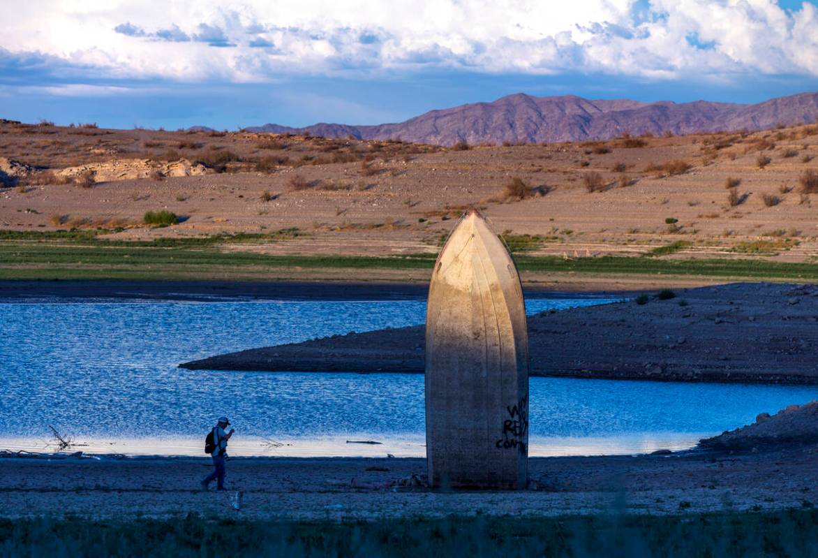 Photographer Mario Tama walks as the late-day light illuminates a boat is stuck straight up alo ...