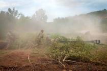 Ukrainian soldiers camouflage a U.S.-supplied M777 howitzer with tree branches after they fired ...