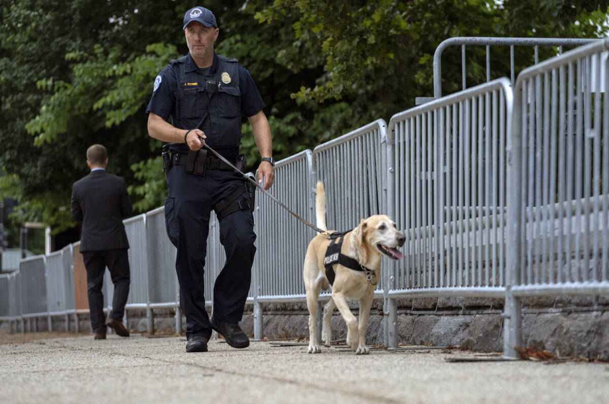A police officer leads a K-9 in the street outside of the U.S. Supreme Court in Washington, Thu ...