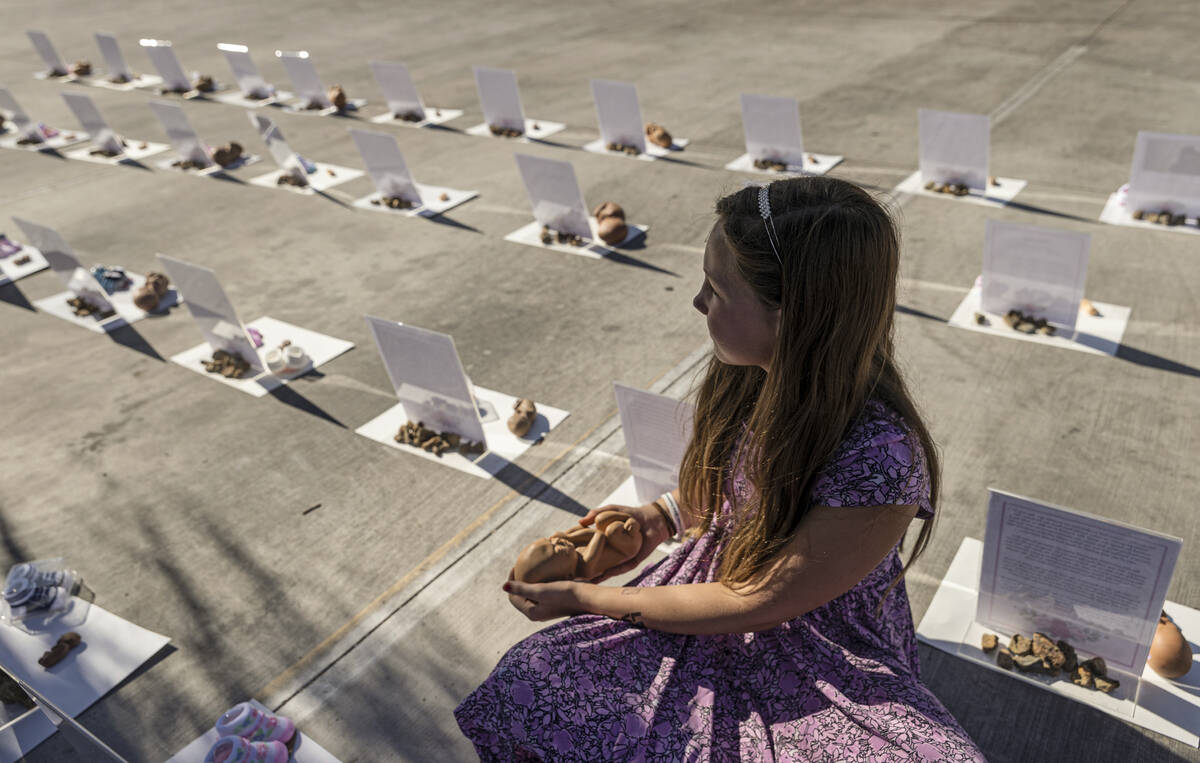 Cherish Berkey, 10, looks out at a memorial to the unborn display while holding a replica of an ...
