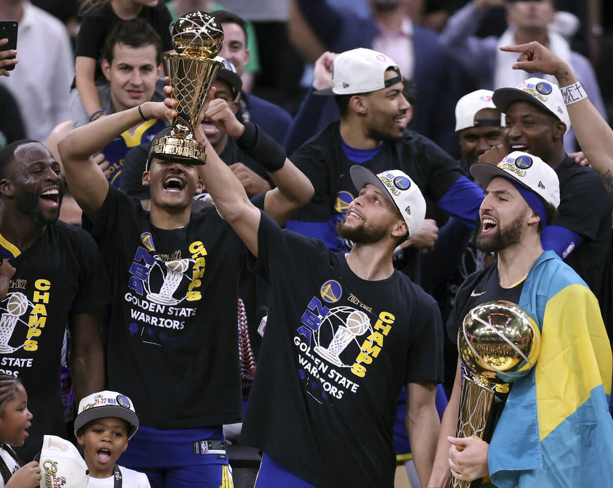 Golden State Warriors' Stephen Curry holds the MVP trophy as Klay Thompson holds the Larry O'Br ...